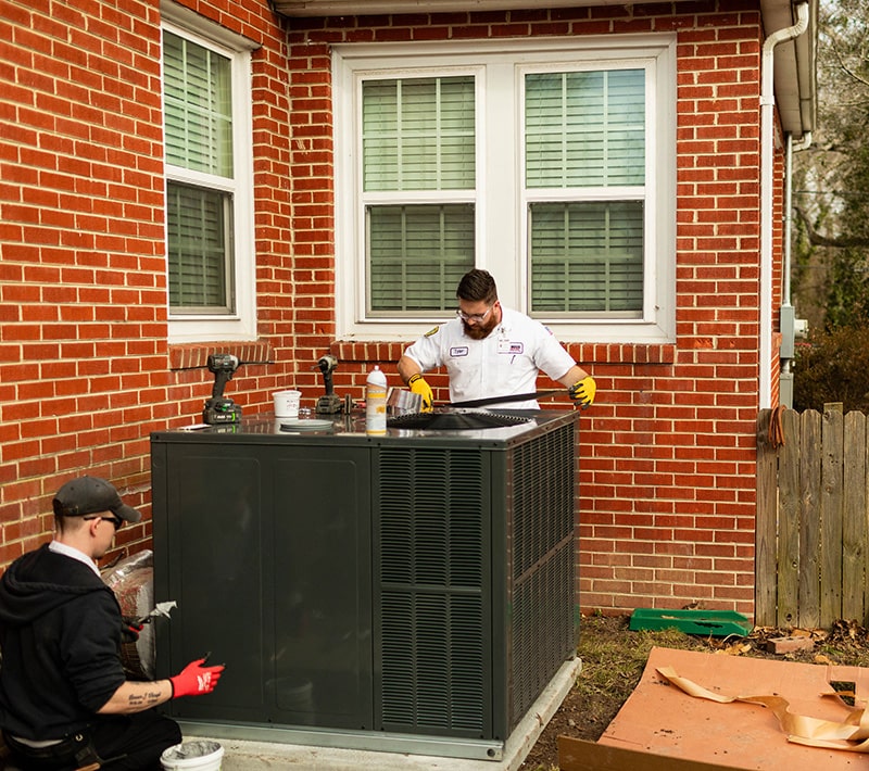 One Hour technician servicing a residential HVAC condenser unit